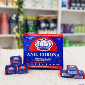 Caja de Añil Corona, el famoso jabón azulito, junto a cubitos individuales sobre un mantel blanco, en exhibición de tienda